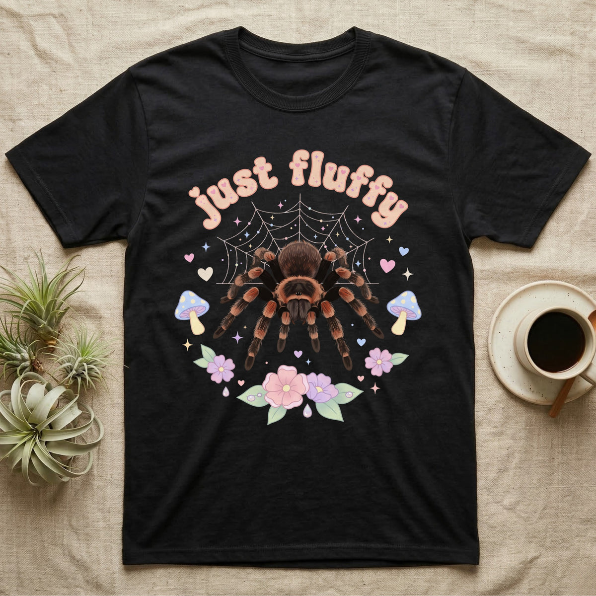 Mexican Redknee Tarantula Baby T-Shirt in Black — Fuzzy Mexican redknee tarantula on a pastel web with blossoms under puffy peach bubble text "just fluffy".