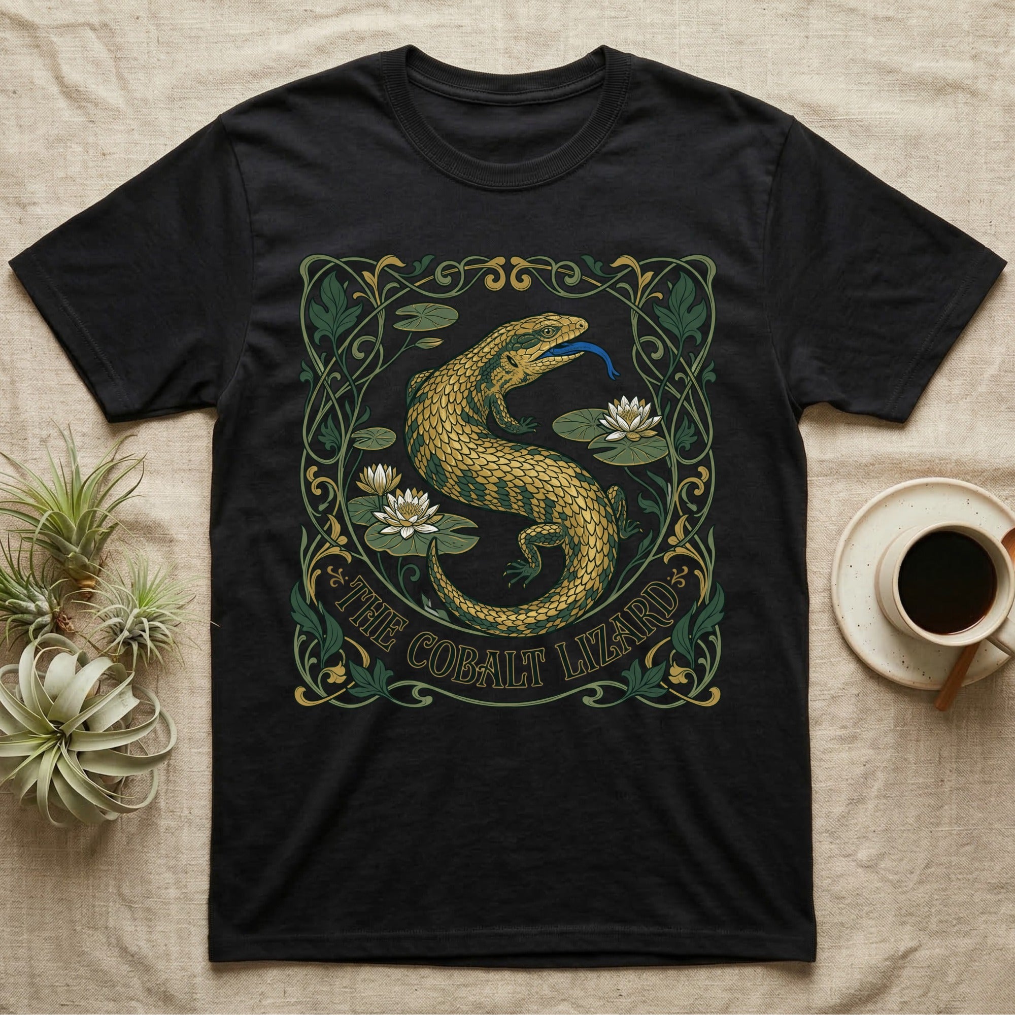 Black t-shirt with a green and gold lizard, lilies, and "The Cobalt Lizard" text.