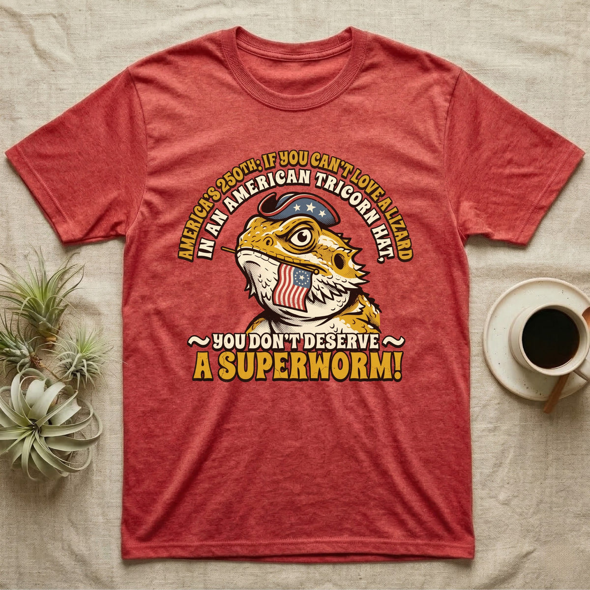 Bearded Dragon Tricorn Tee in Heather Red — Bold woodcut tee of a bearded dragon in a colonial tricorn hat, gold and cream text reading You Don't Deserve A Superworm, on black.