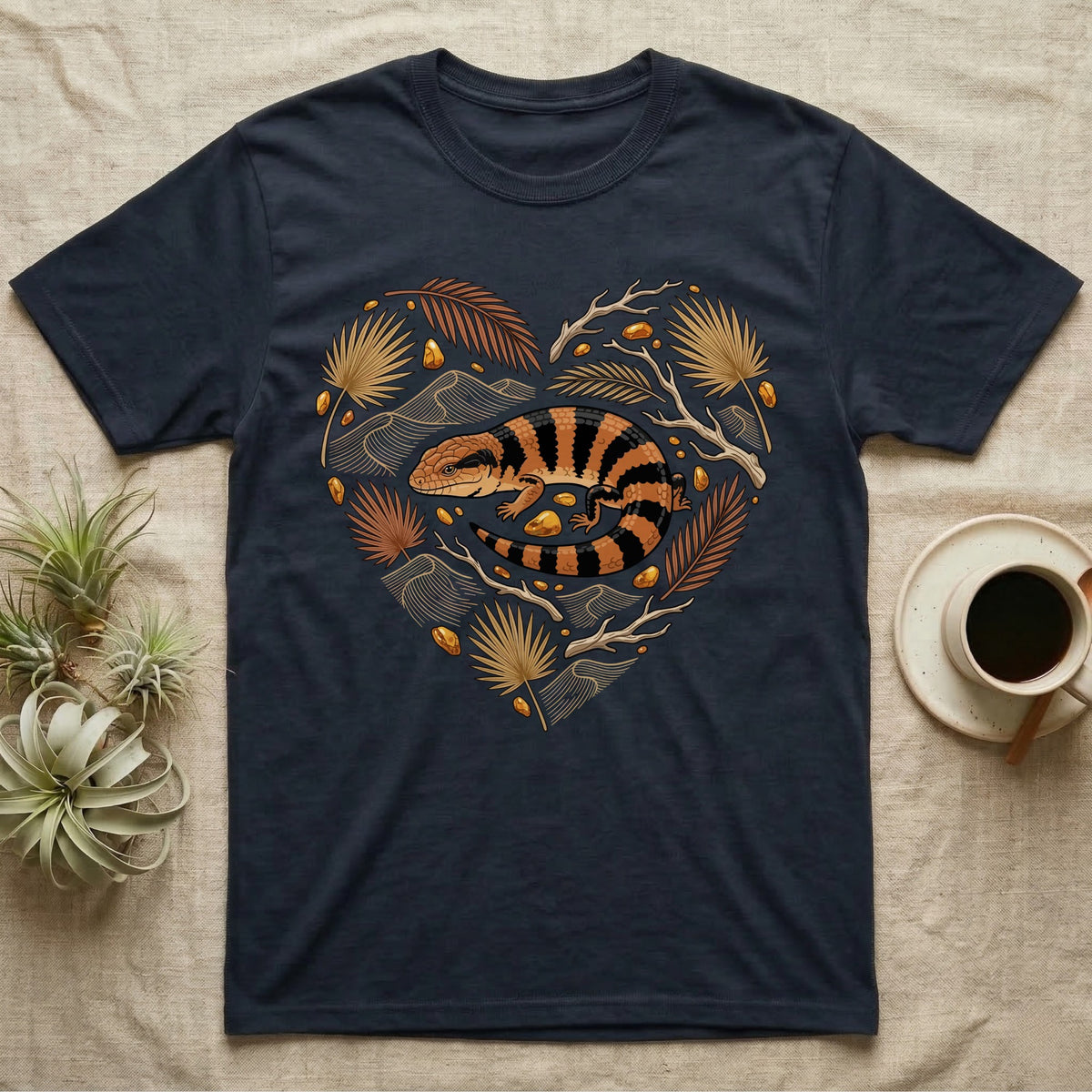 Dark t-shirt with heart-shaped design of a blue-tongued skink and golden leaves.