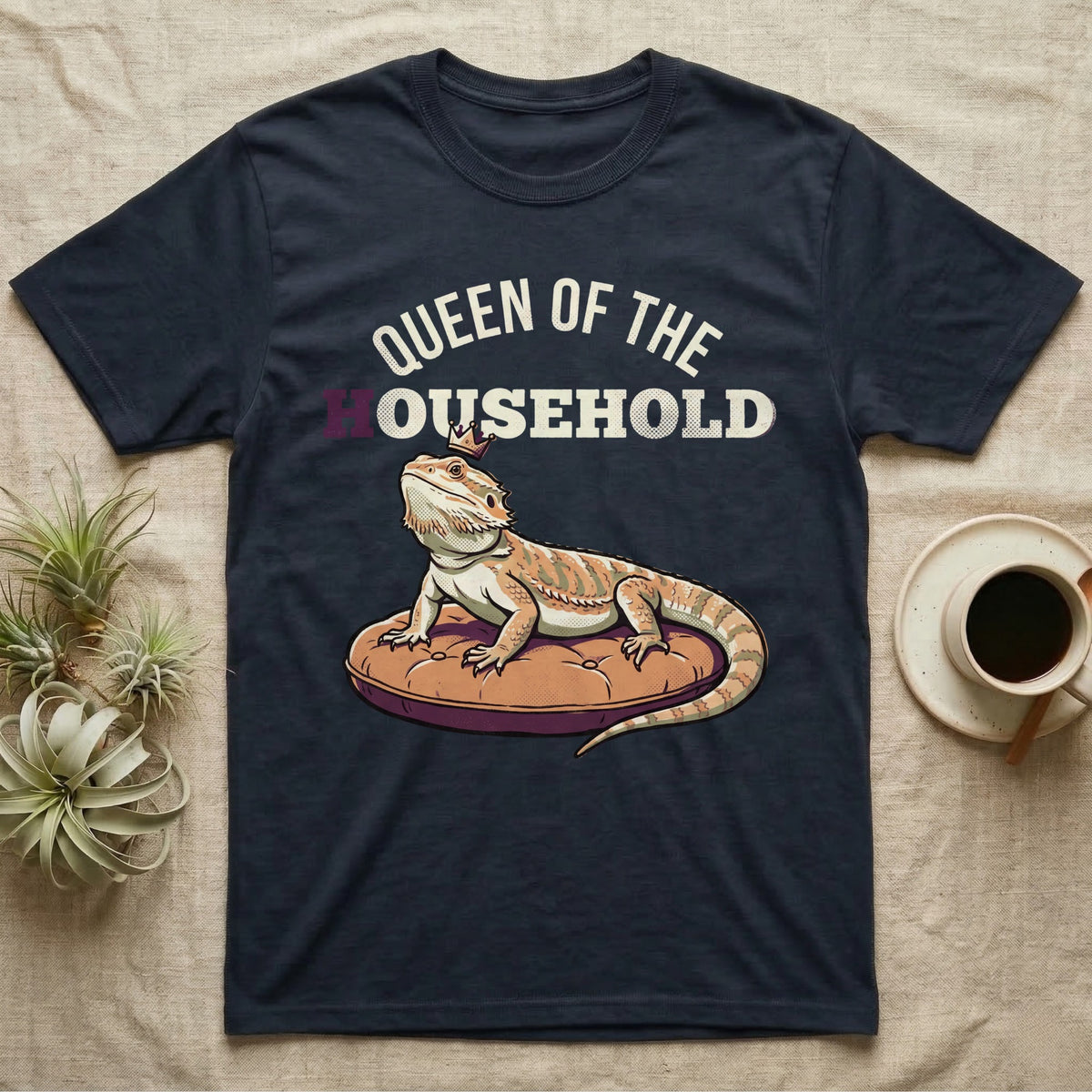 Queen Bearded Dragon T-Shirt in Navy — Bold-vector illustration of a bearded dragon on a throne-cushion with a crown under varsity Queen of the Household lettering.