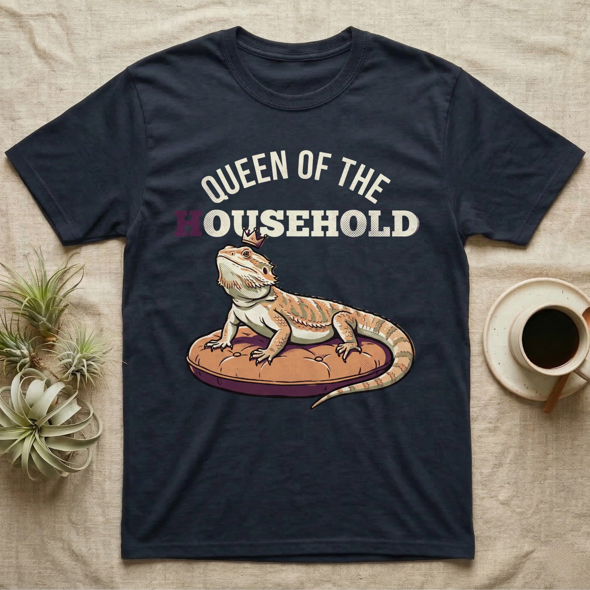 Queen Bearded Dragon T-Shirt in Navy — Bold-vector illustration of a bearded dragon on a throne-cushion with a crown under varsity Queen of the Household lettering.