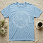 Ackie Monitor Roundel T-Shirt in Light Blue — Two ackie monitors in fine white line art, mirrored at 180 degrees around a tiny heart, tails sweeping outward.