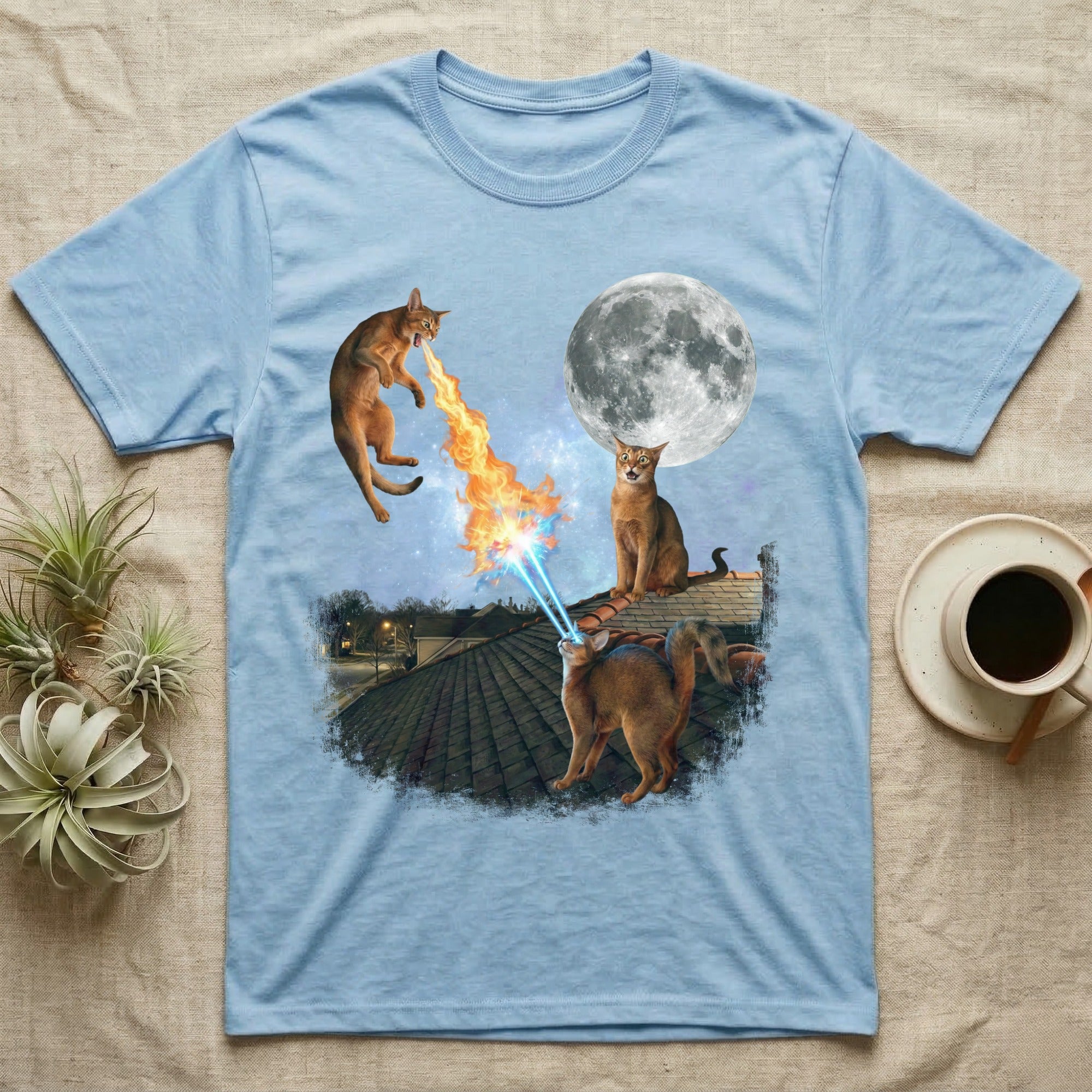 Light blue t-shirt with cats shooting lasers and fire at a moon.