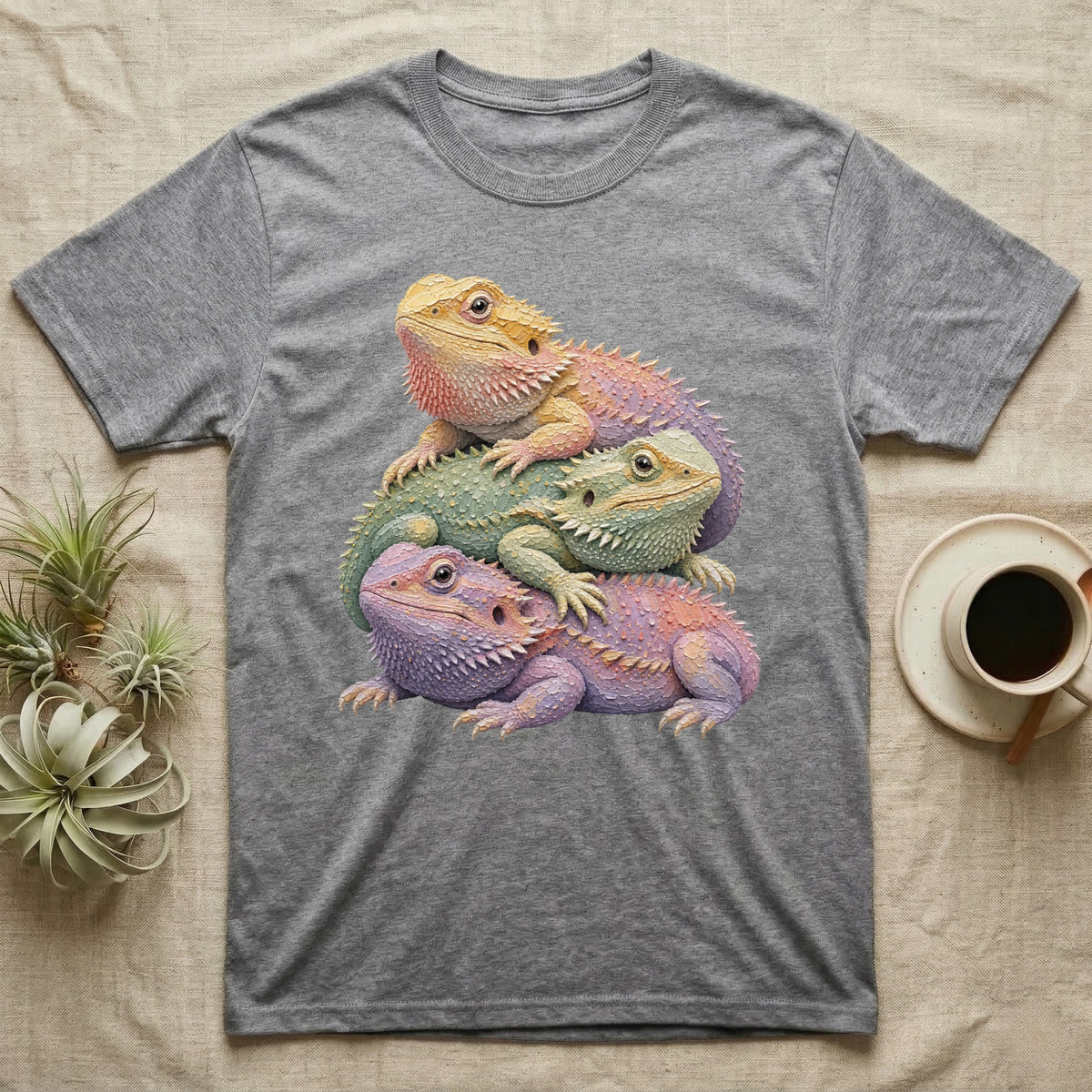 Three colorful bearded dragons stacked on a grey t-shirt.