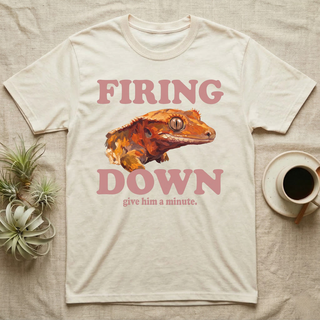 Crested Gecko Firing Down T-Shirt in Natural — Engraved crested gecko in navy ink between the rose words Firing and Down, with give him a minute above.