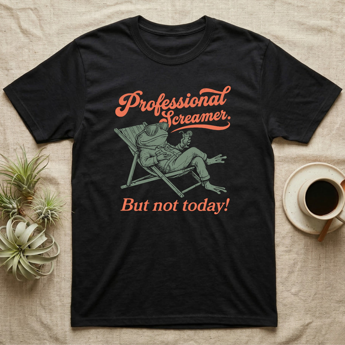 Budgett's Frog Day Off T-Shirt in Black — Illustrated Budgett's frog lounging in a beach chair in a jacket with sunglasses and a cocktail, coral script reading Professional Screamer But Not Today.