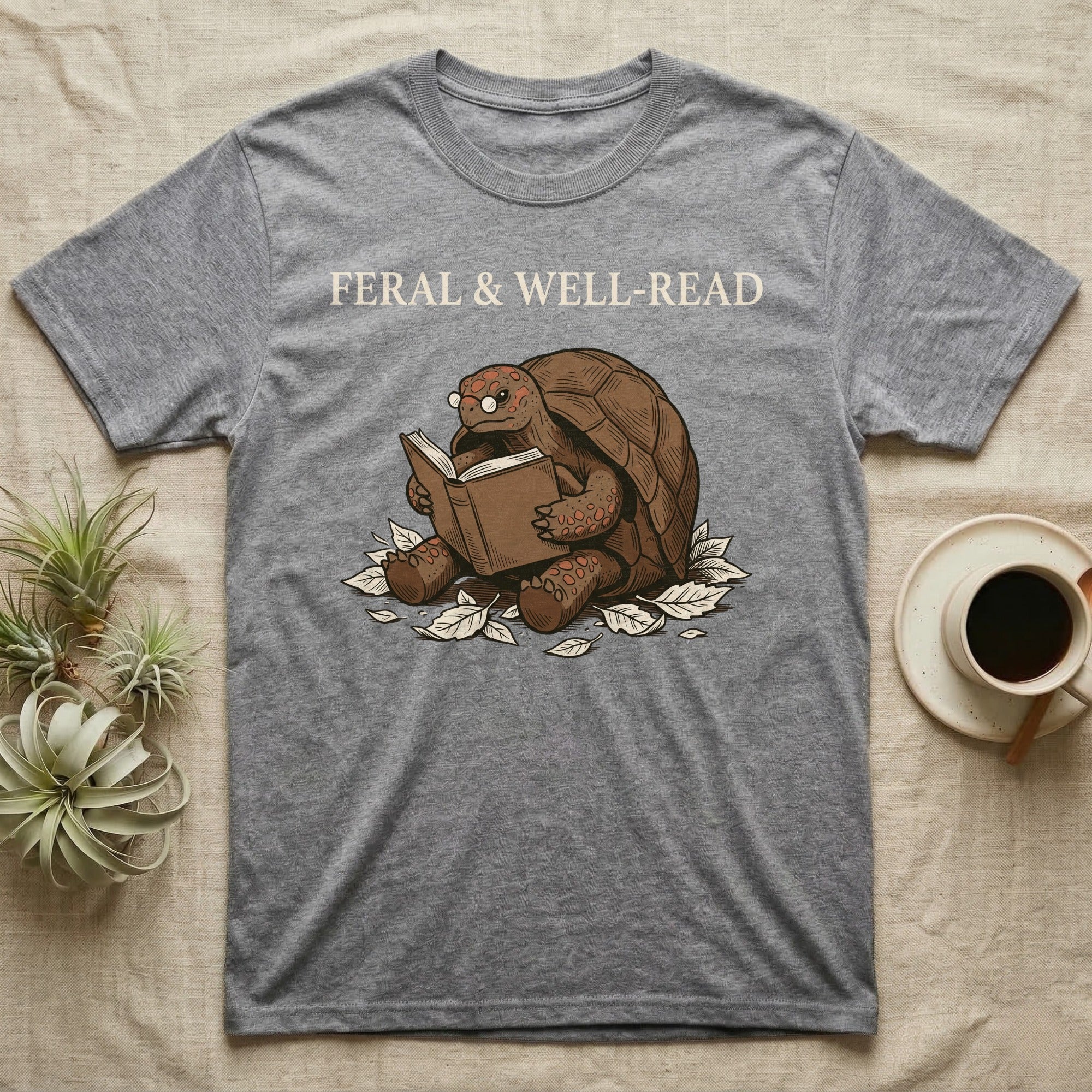 Red-Foot Tortoise Reading T-Shirt in Sport Grey — Pen-and-ink red-foot tortoise seated reading a book in tiny glasses with cross-hatch shading and cream ink