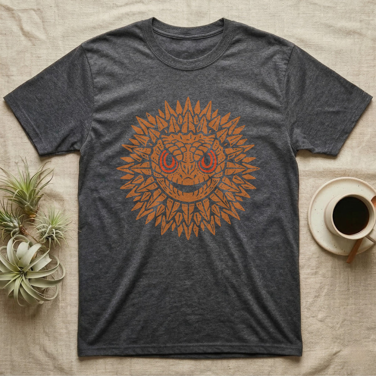 Crocodile Skink Tiny Dragon T-Shirt in Dark Heather — Frontal red-eyed crocodile skink head with dorsal spines flared into an ochre sunburst medallion, red eye ring.