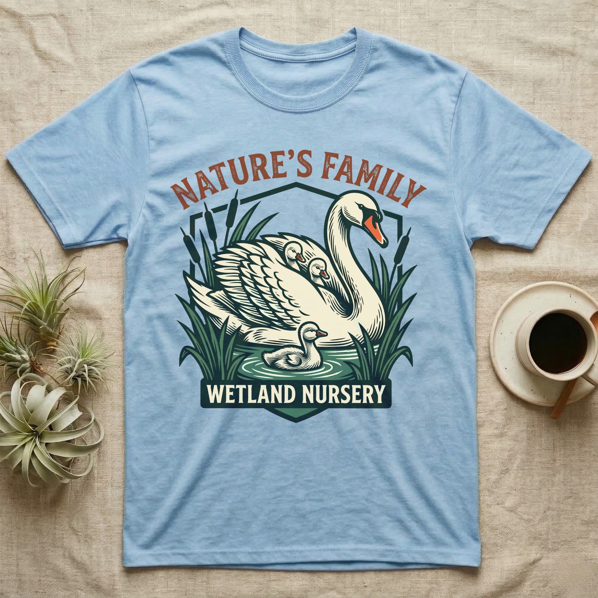 Light blue t-shirt with "Nature's Family Wetland Nursery" graphic of swans and ducklings.