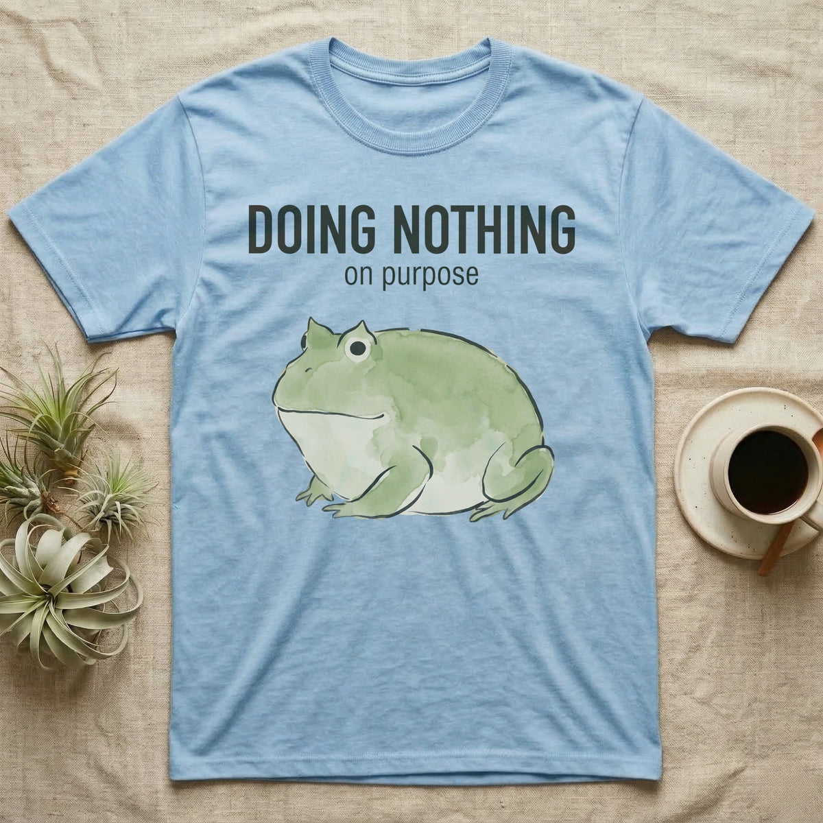 Pacman Frog Doing Nothing T-Shirt in Light Blue — Watercolour pacman frog blob in profile below the words doing nothing on purpose, on grey