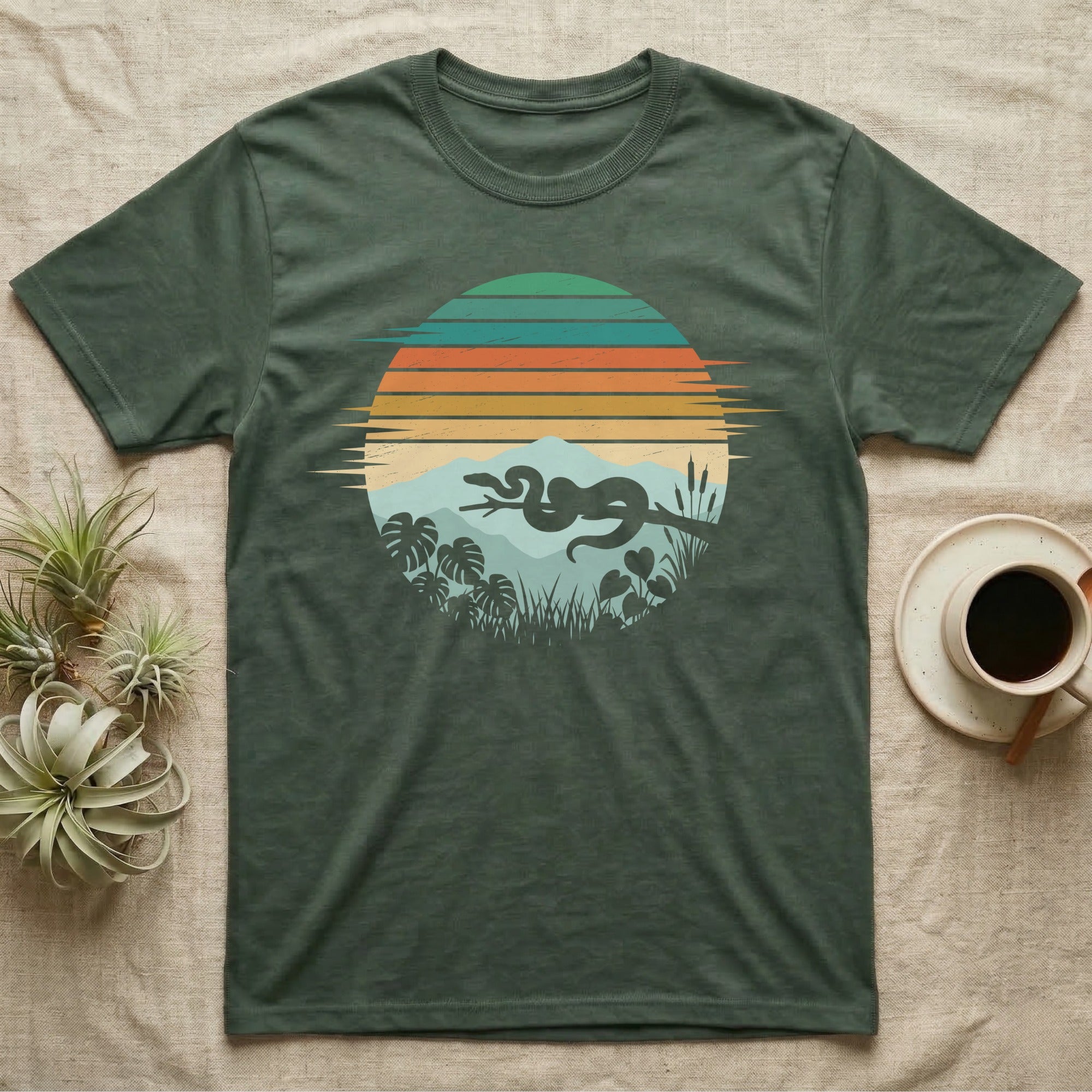 Ball Python Retro Sunset T-Shirt in Military Green — Ball python silhouette draped over a branch inside a retro striped sunset disc with monstera leaves on a tee