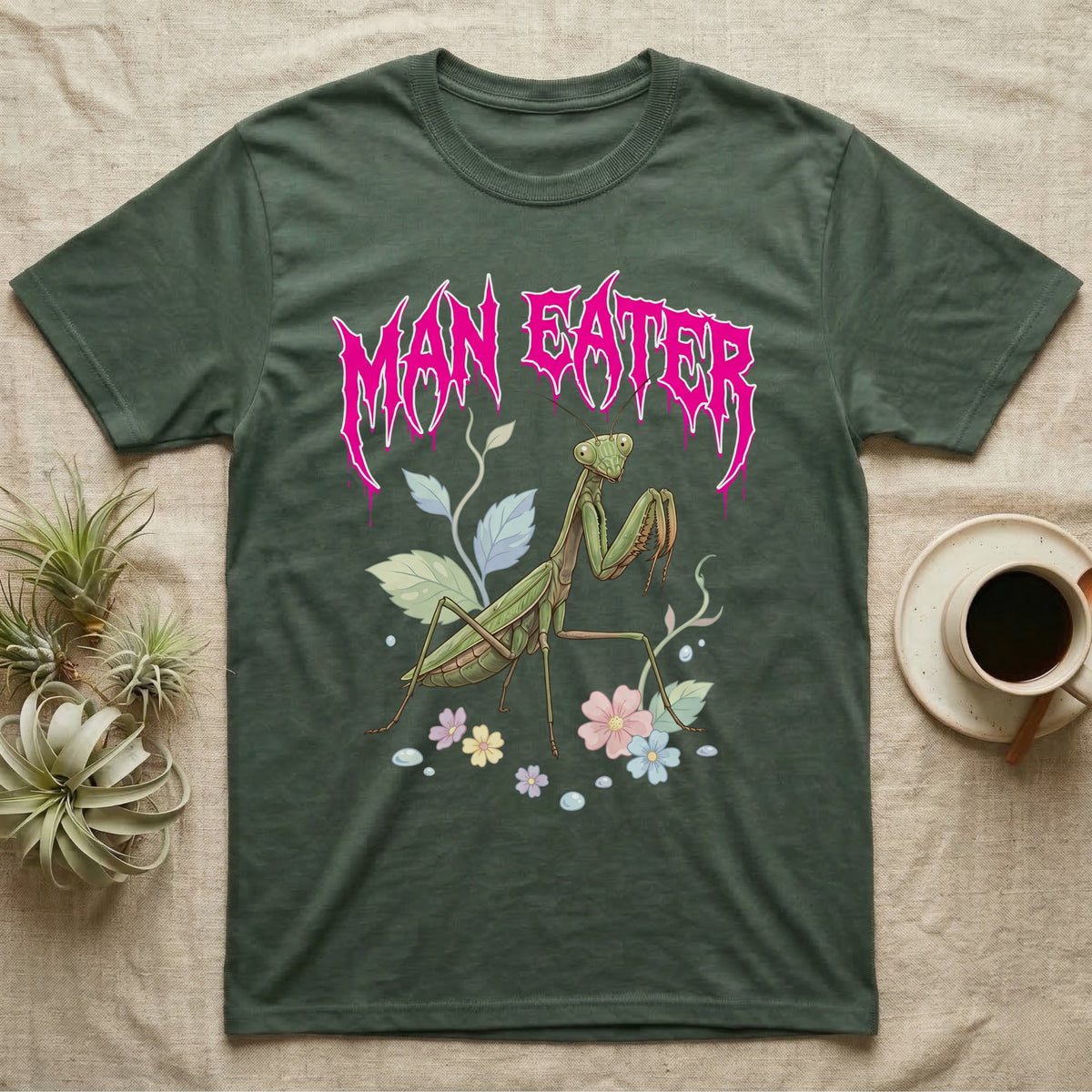 Chinese Mantis Feral T-Shirt in Military Green — Pastel Chinese mantis with raised spiked forelegs among leaves and blossoms, jagged magenta metal wordmark "MAN EATER" above.