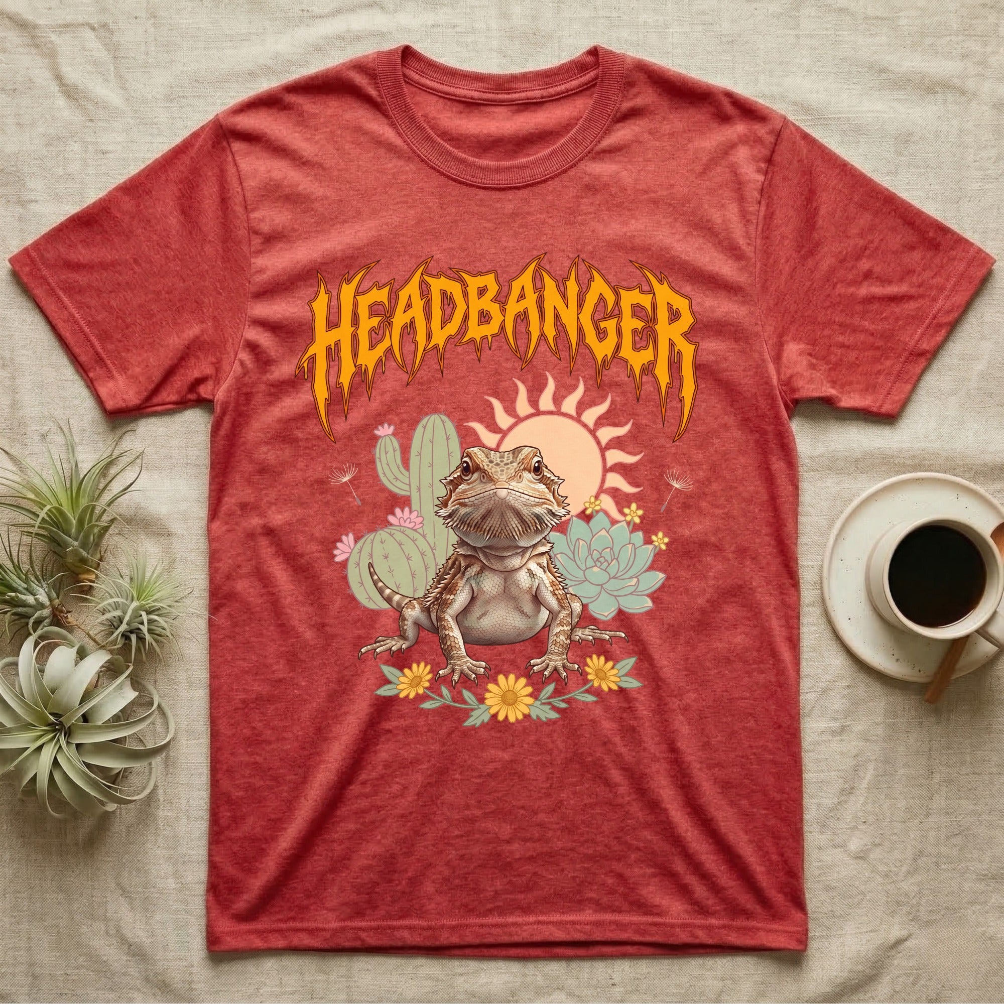 Central Bearded Dragon Feral T-Shirt in Heather Red — Baby bearded dragon in a pastel desert scene under a spiky amber metal wordmark reading HEADBANGER.