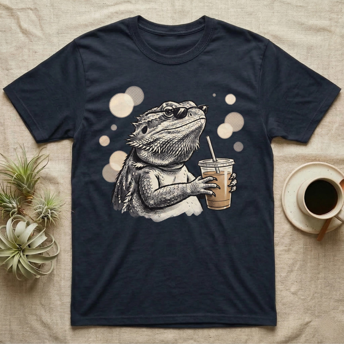 Cold Brew Bearded Dragon T-Shirt in Navy — Flat near-photoreal illustration of a bearded dragon in tiny sunglasses holding a cold brew with warm bokeh.