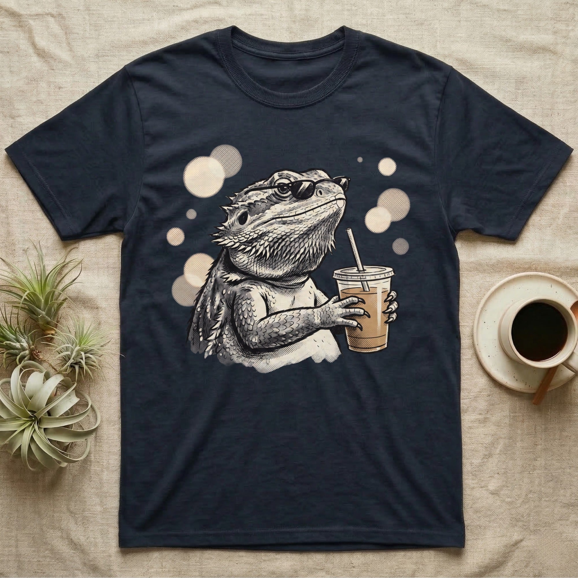Cold Brew Bearded Dragon T-Shirt in Navy — Flat near-photoreal illustration of a bearded dragon in tiny sunglasses holding a cold brew with warm bokeh.