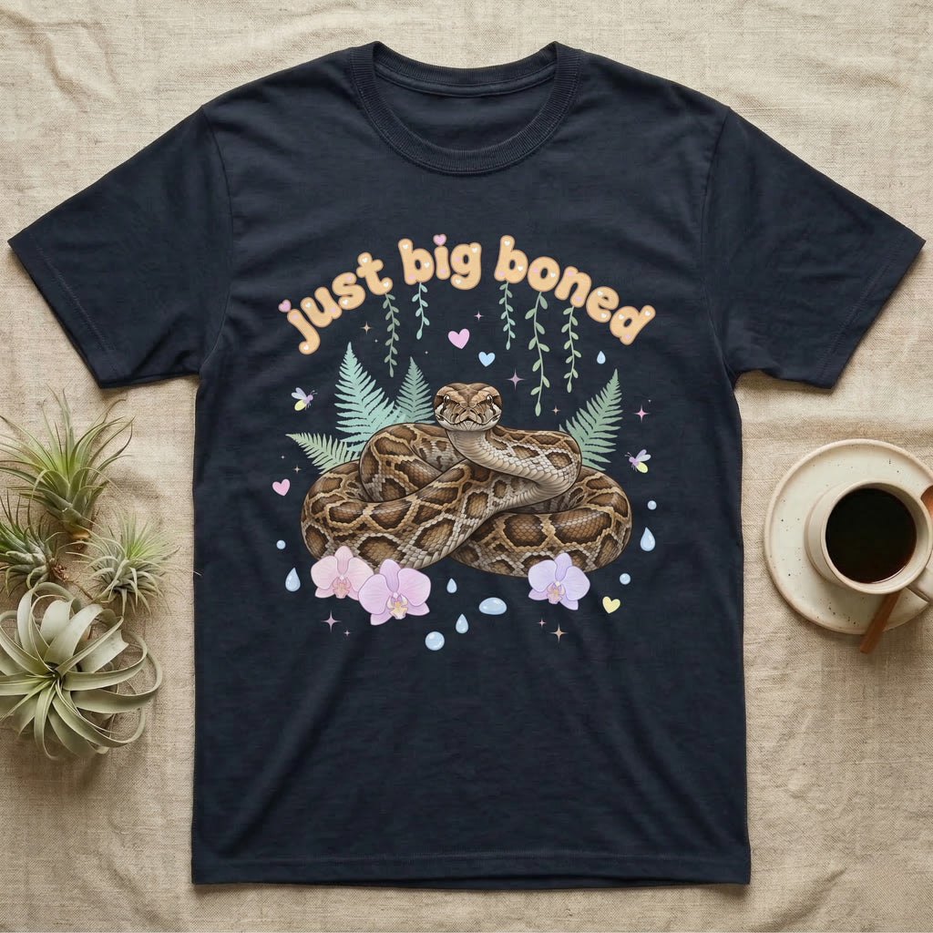 Burmese Python Baby T-Shirt in Navy — Massive coiled Burmese python among pastel ferns and orchids under puffy butterscotch bubble text "just big boned".