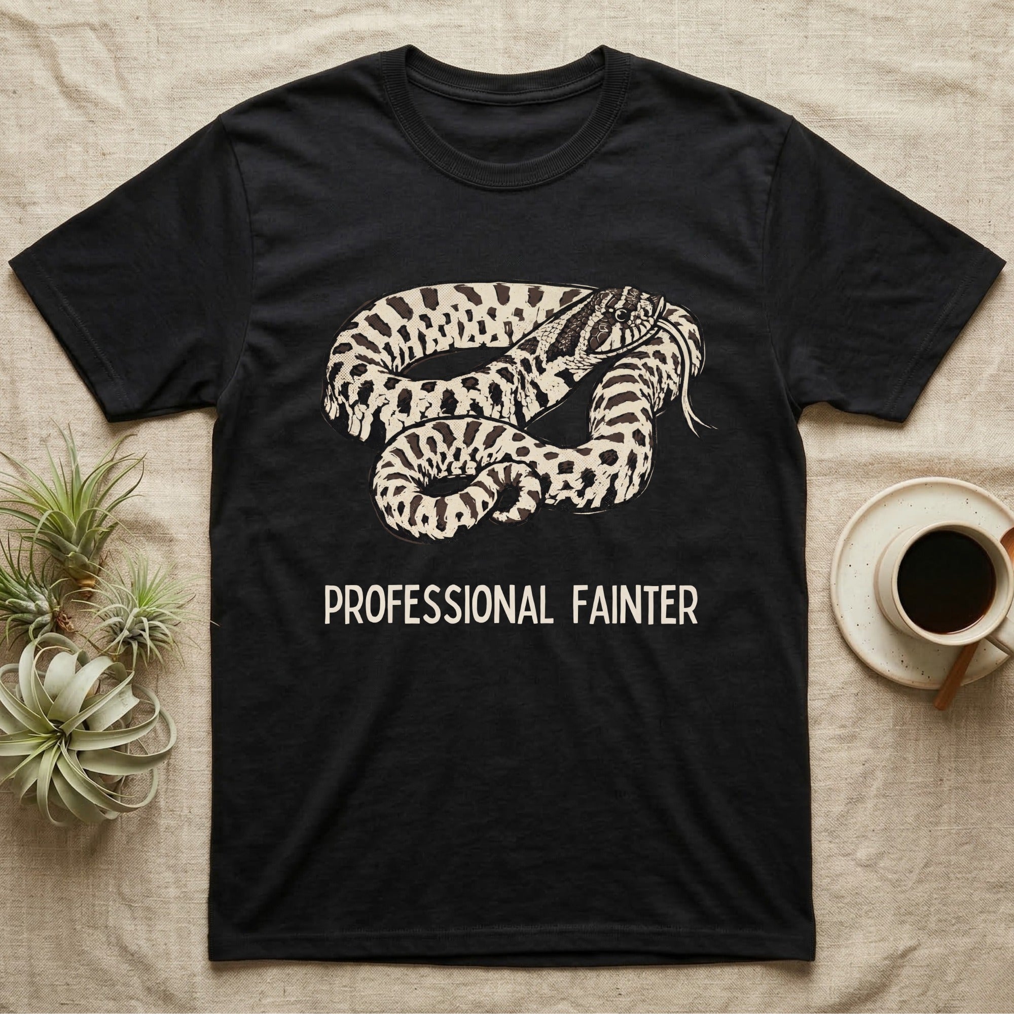 Hognose Professional Fainter T-Shirt in Black — Linocut block-print of a western hognose snake flopped belly-up in a death-feign with professional fainter caption.