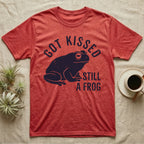 Tree Frog Kissed T-Shirt in Heather Red — Worn navy silhouette of a dumpy White's tree frog under the words Got Kissed Still A Frog