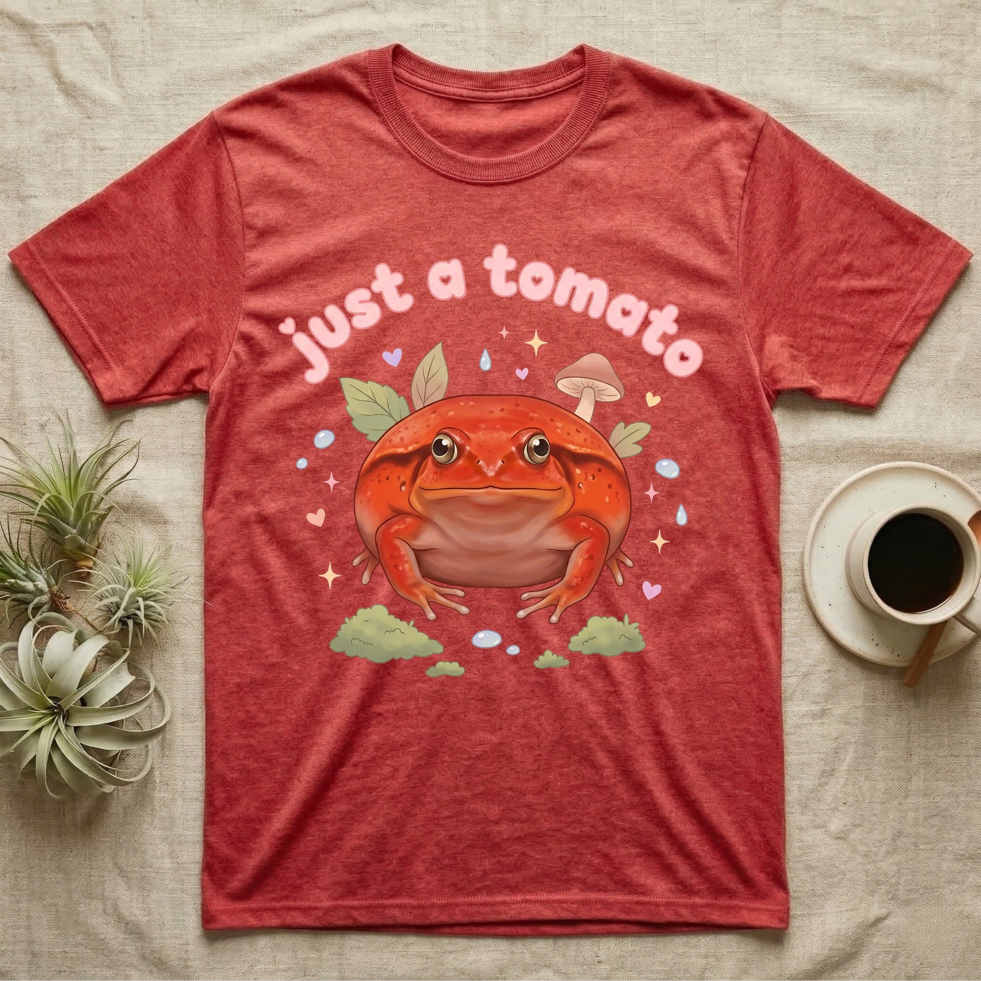 Tomato Frog Softie T-Shirt in Heather Red — Round red-orange tomato frog facing forward under a puffy pastel "just a tomato" bubble wordmark with tiny hearts.