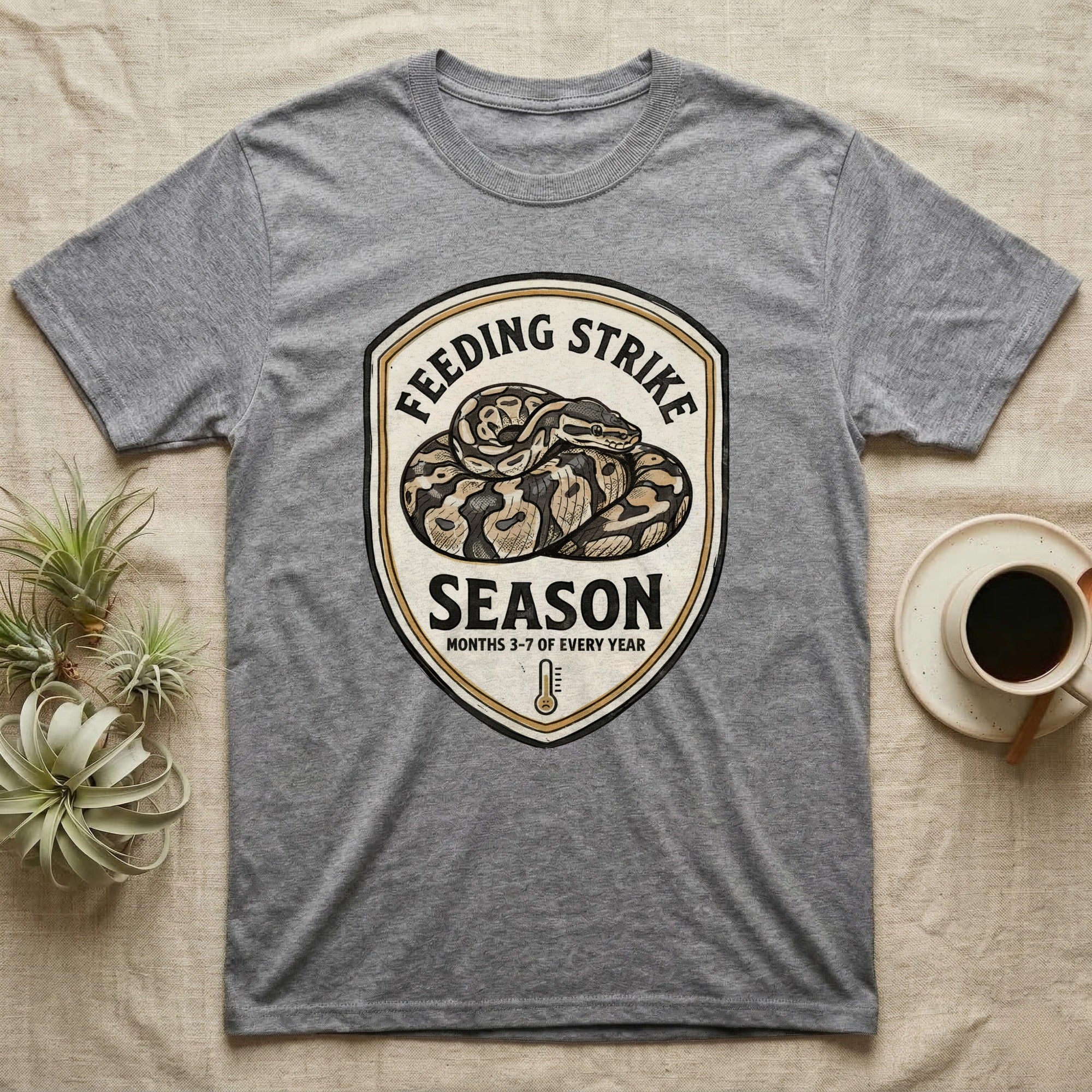 Ball Python Feeding Strike T-Shirt in Sport Grey — Vintage-ink badge of a coiled ball python with carved type "Feeding Strike Season" and fine print "Months 3-7 Of Every Year."