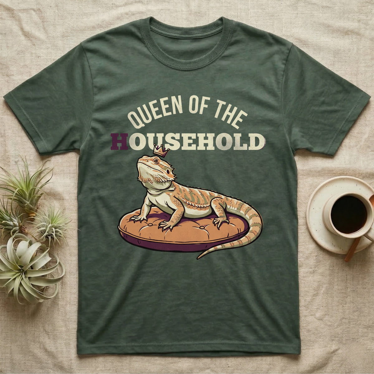 Queen Bearded Dragon T-Shirt in Military Green — Bold-vector illustration of a bearded dragon on a throne-cushion with a crown under varsity Queen of the Household lettering.