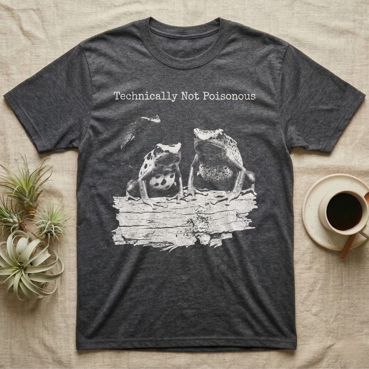 Technically Not Poisonous Dart Frog T-Shirt in Dark Heather — Three blue poison dart frogs on a bark ledge in distressed screen-print style under the line Technically Not Poisonous.