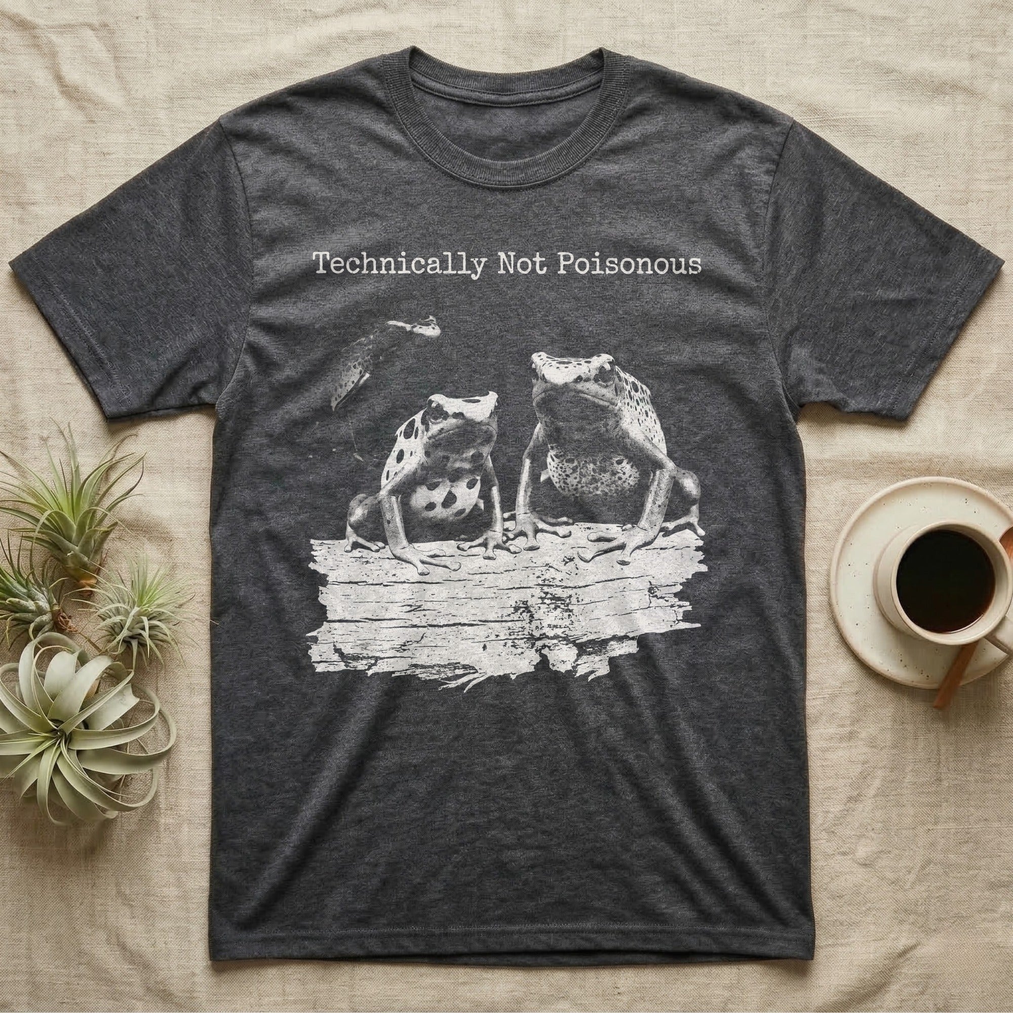 Technically Not Poisonous Dart Frog T-Shirt in Dark Heather — Three blue poison dart frogs on a bark ledge in distressed screen-print style under the line Technically Not Poisonous.