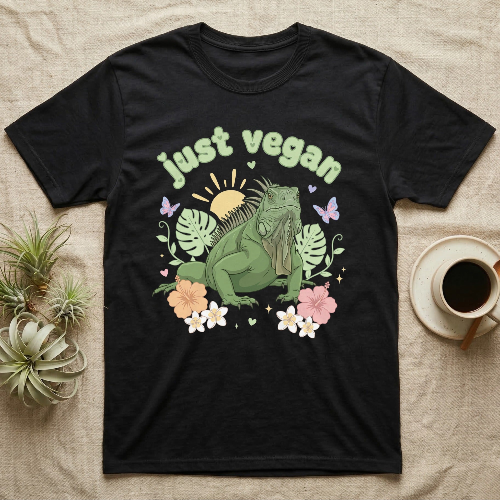 Green Iguana Baby T-Shirt in Black — Green iguana with spiky crest and dewlap among pastel leaves and flowers under puffy green bubble text "just vegan".