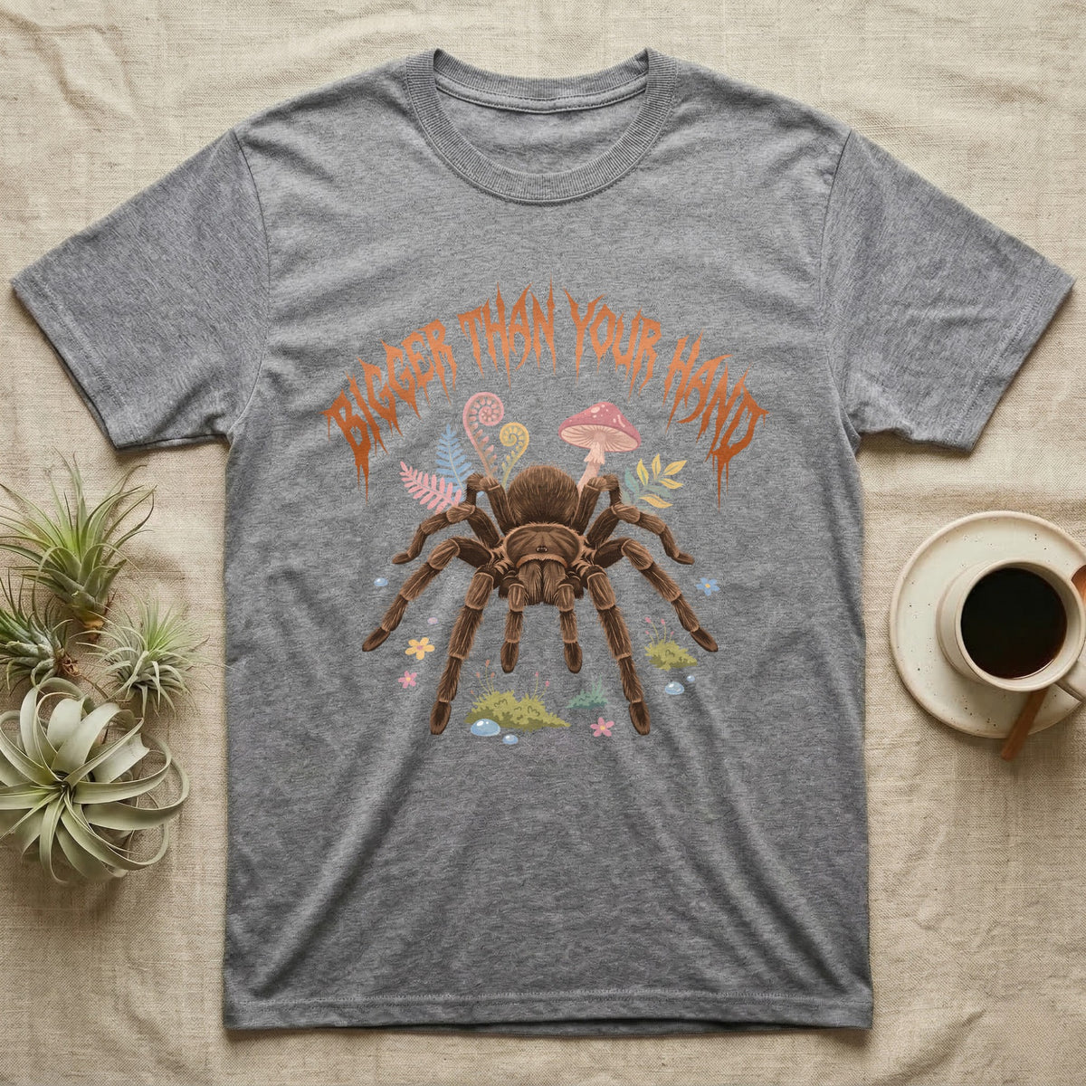 Goliath Birdeater Feral T-Shirt in Sport Grey — Goliath birdeater tarantula with bristly legs spread under jagged copper metal text BIGGER THAN YOUR HAND