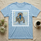 Light blue t-shirt featuring a stamp with a lizard, "USA POSTAGE 37 CENTS", and Japanese text.