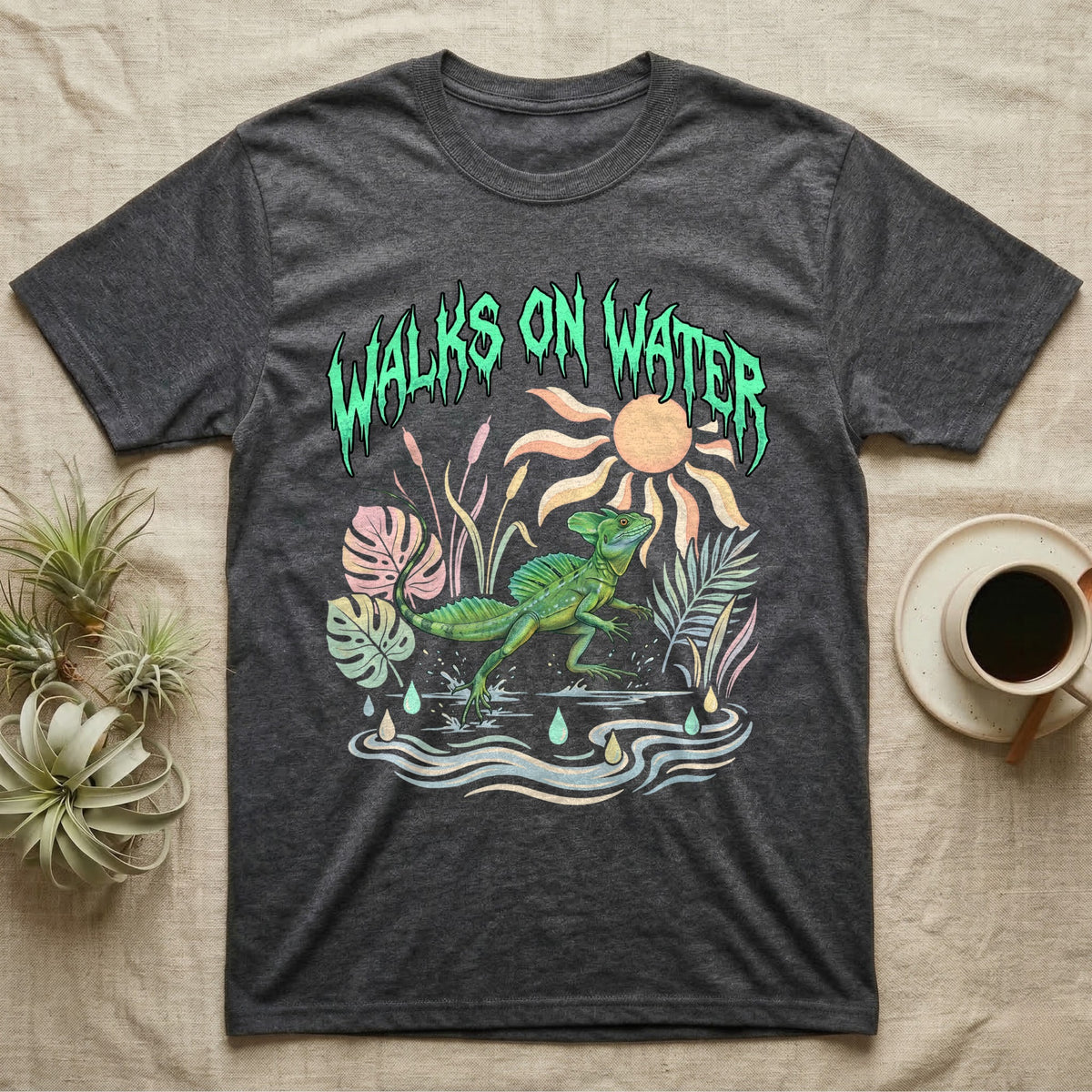 Green Basilisk Feral T-Shirt in Dark Heather — Green plumed basilisk sprinting across water below a dripping aqua-green metal "Walks On Water" wordmark