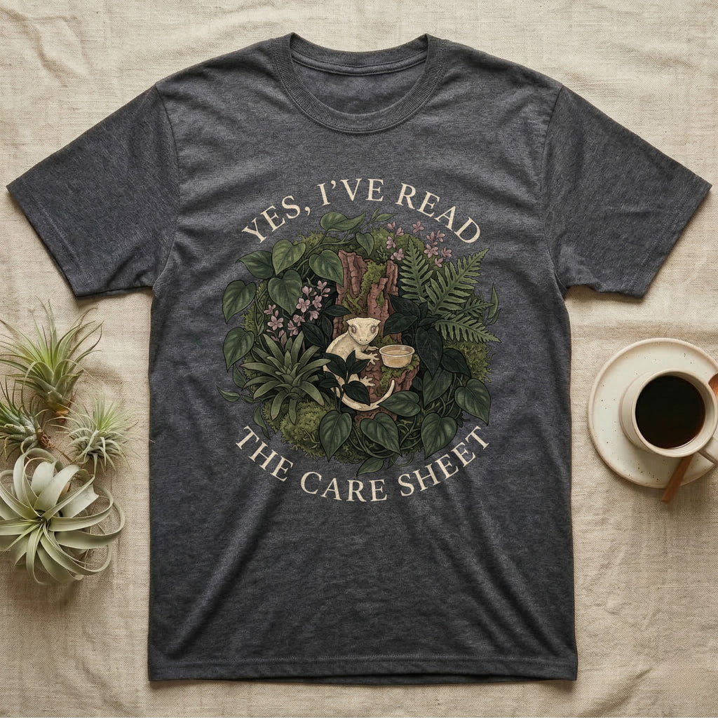 Crested Gecko Care Sheet T-Shirt in Dark Heather — Botanical wreath of pothos and moss circling a crested gecko, closed by two arcs of Roman capitals.