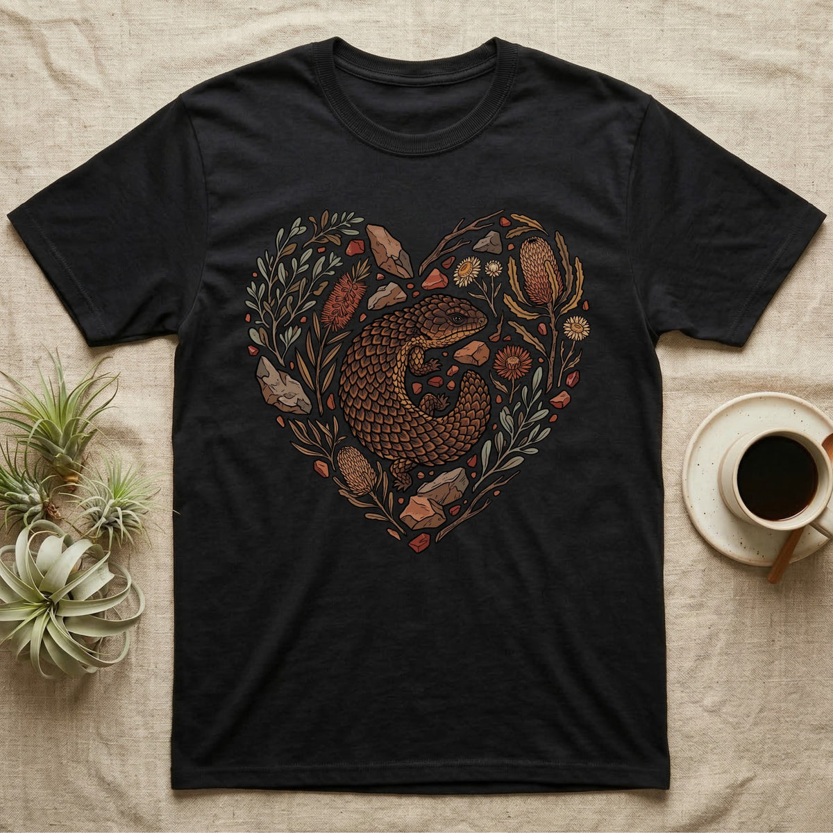 Black t-shirt with heart-shaped naturalistic illustration of a lizard and flora.