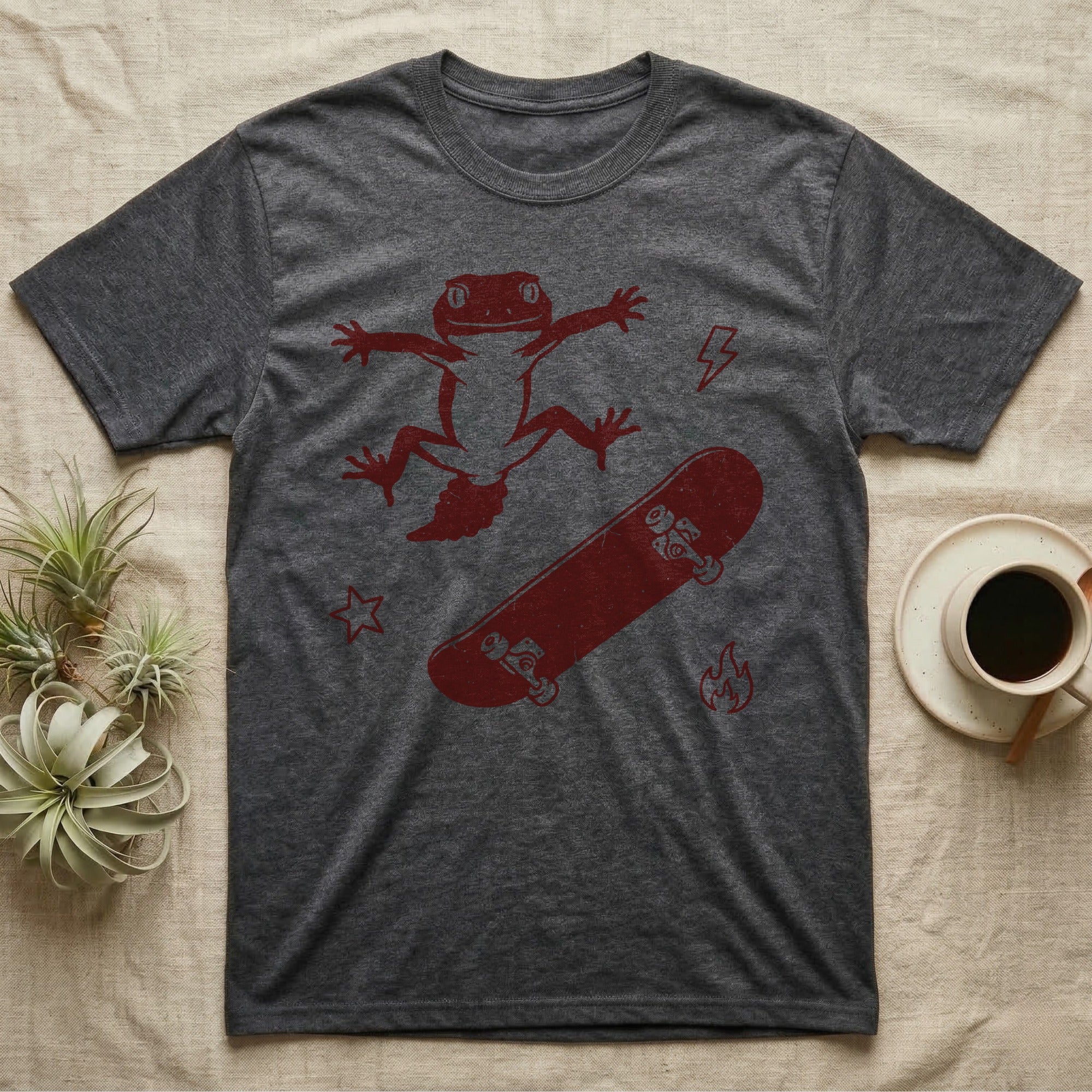 Knob-Tailed Gecko Kickflip T-Shirt in Dark Heather — Distressed one-ink illustration of a knob-tailed gecko airborne mid-kickflip above a tumbling skateboard.