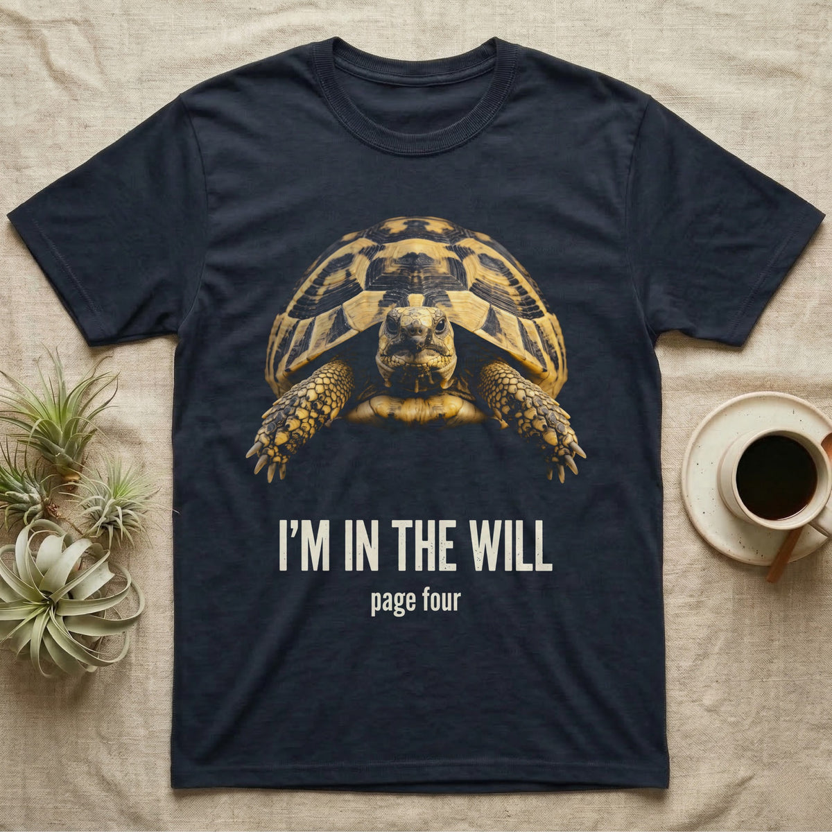 Flat-black mug-shot portrait of a Hermann's tortoise peering from its domed shell, with the printed words I'm In The Will, page four. — shown on a Navy tee.