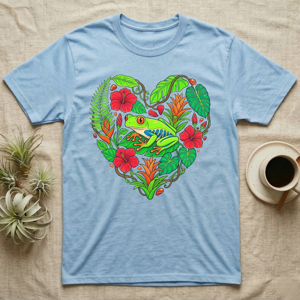 Light blue t-shirt with a heart-shaped tropical foliage and frog design.
