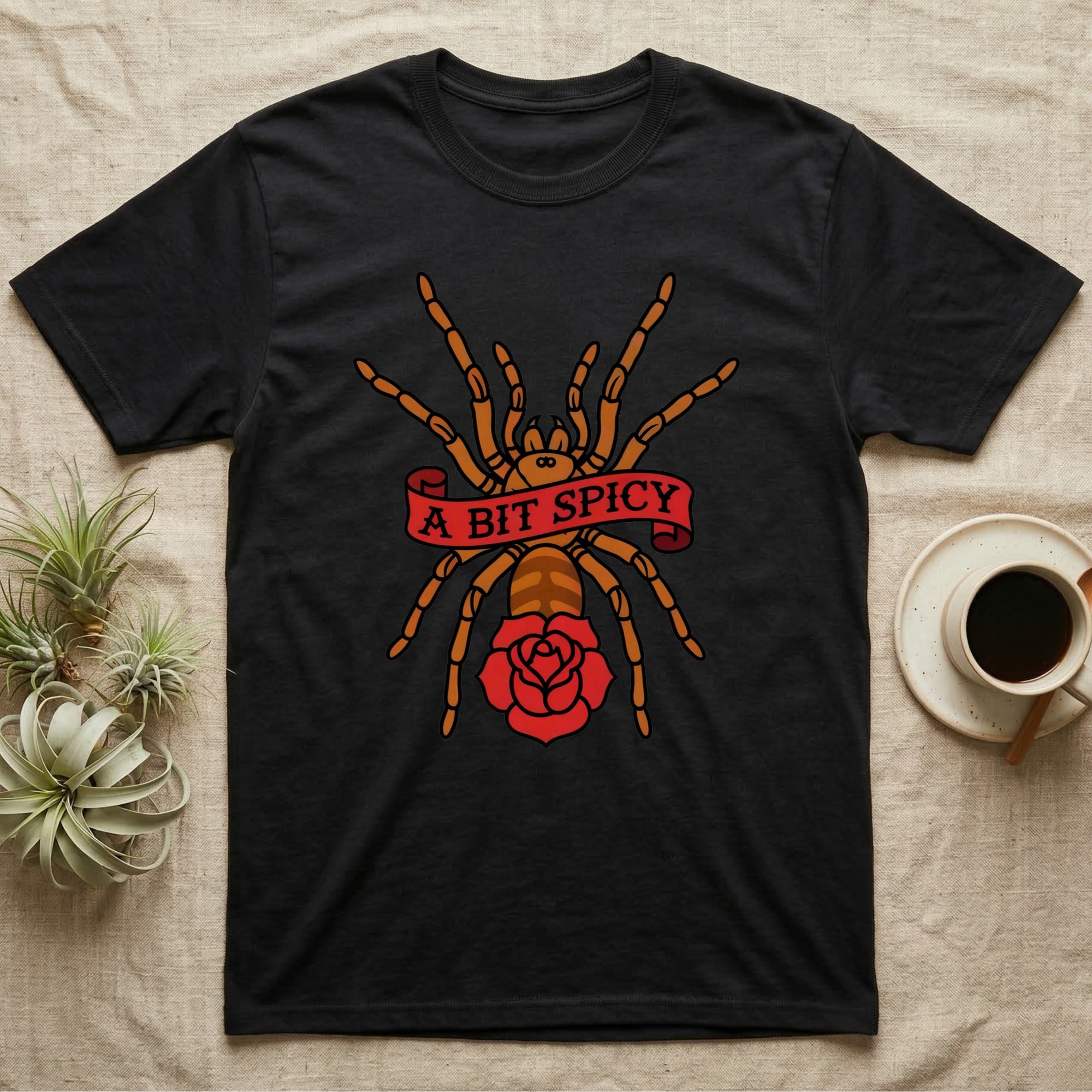 Tarantula A Bit Spicy T-Shirt in Black — Tattoo-flash orange-baboon-tarantula in threat-pose with banner-scroll "A Bit Spicy" and a flash rose beneath.