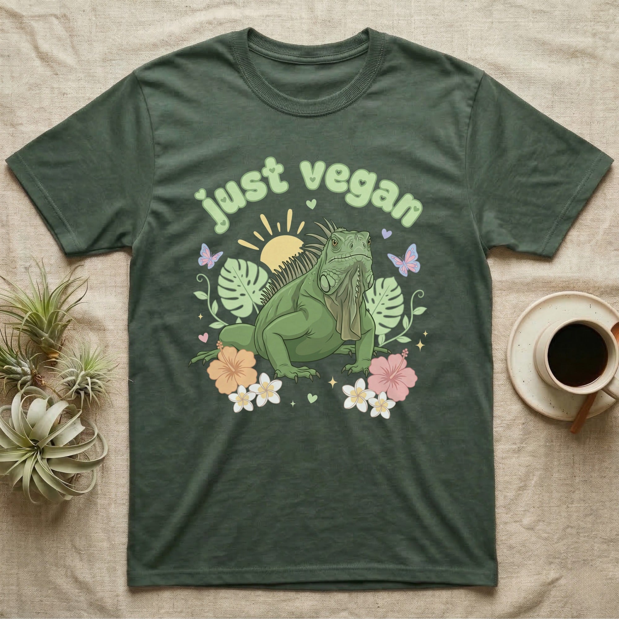 Green Iguana Baby T-Shirt in Military Green — Green iguana with spiky crest and dewlap among pastel leaves and flowers under puffy green bubble text "just vegan".