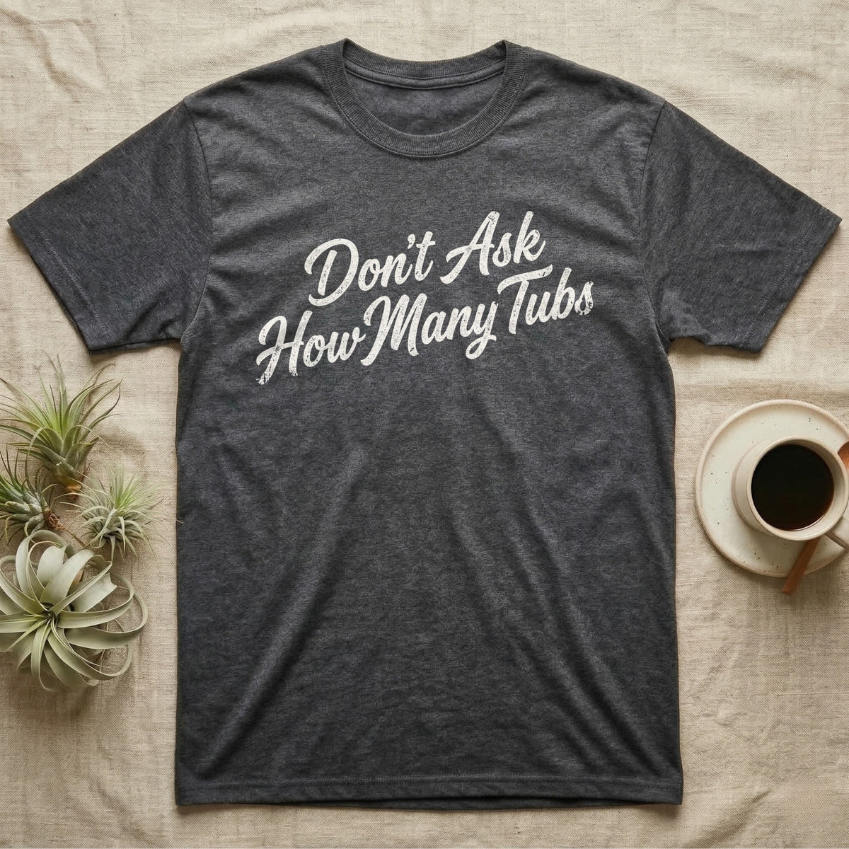 Snake Tubs T-Shirt in Dark Heather — Worn off-white 1970s retro brush script climbing a diagonal on charcoal, reading Don't Ask How Many Tubs
