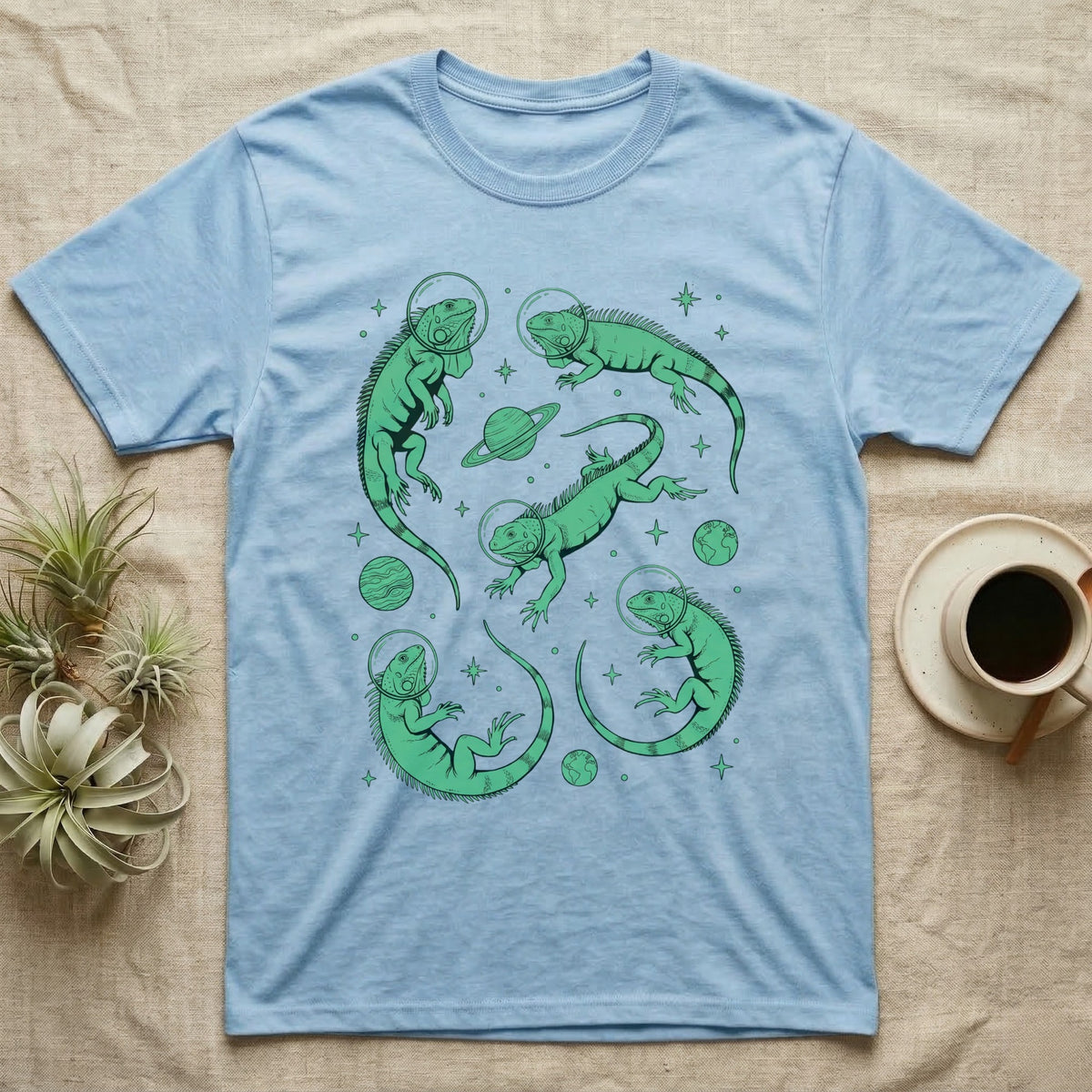 Green Iguana Cosmic T-Shirt in Light Blue — Vintage screen-print illustration of green iguanas in astronaut helmets floating in space, cosmic emerald green monochromatic on dark background.