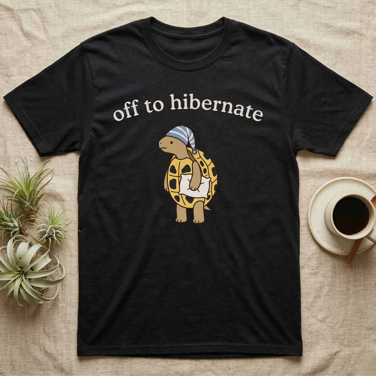 Hermann's Tortoise Hibernation T-Shirt in Black — Minimal doodle of a Hermann's tortoise in a striped nightcap holding a pillow under the words off to hibernate