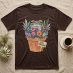 Tree Frog Thriving T-Shirt in Dark Chocolate — A White's tree frog made of watercolour flowers, sitting in a terracotta pot with a plant label reading STILL THRIVING.