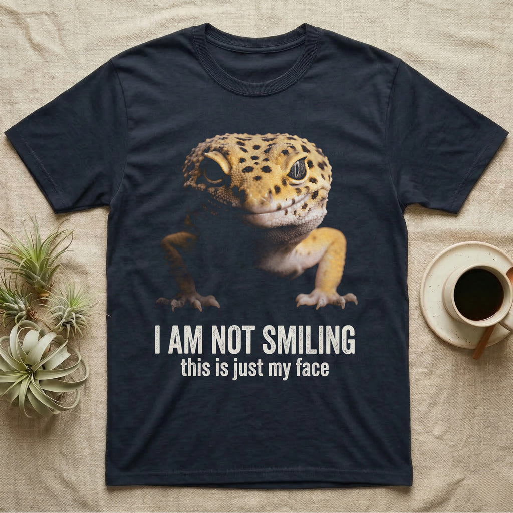 Photographic mugshot of a leopard gecko braced low and staring into the lens above the hook I Am Not Smiling, this is just my face. — shown on a Navy tee.
