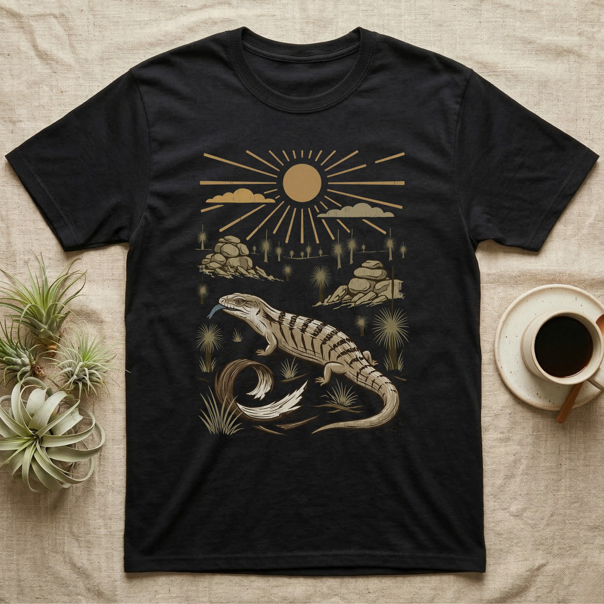 Blue-Tongued Skink Home Range T-Shirt in Black — Woodcut-style illustration of a blue-tongued skink walking across bare soil with its tongue out, shed skin and grass trees behind, no on-shirt text.