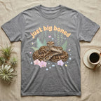 Burmese Python Baby T-Shirt in Sport Grey — Massive coiled Burmese python among pastel ferns and orchids under puffy butterscotch bubble text "just big boned".