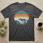 Ball Python Retro Sunset T-Shirt in Dark Heather — Ball python silhouette draped over a branch inside a retro striped sunset disc with monstera leaves on a tee