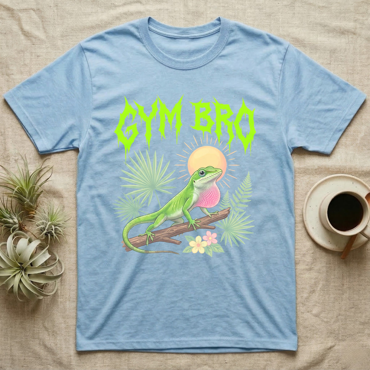Green Anole Feral T-Shirt in Light Blue — Green anole mid push-up with flared pink dewlap under a jagged neon-lime metal "GYM BRO" wordmark and pastel ferns.