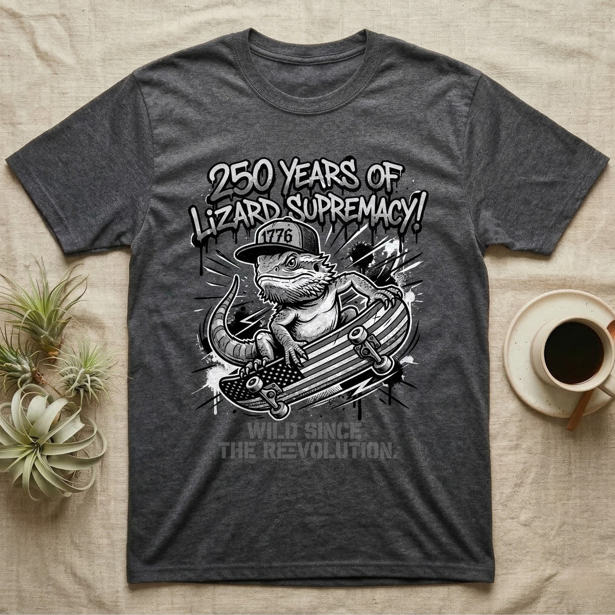 Bearded Dragon Skater T-Shirt in Dark Heather — Black-and-white bearded dragon in a 1776 snapback on a flag skateboard under text 250 Years of Lizard Supremacy.