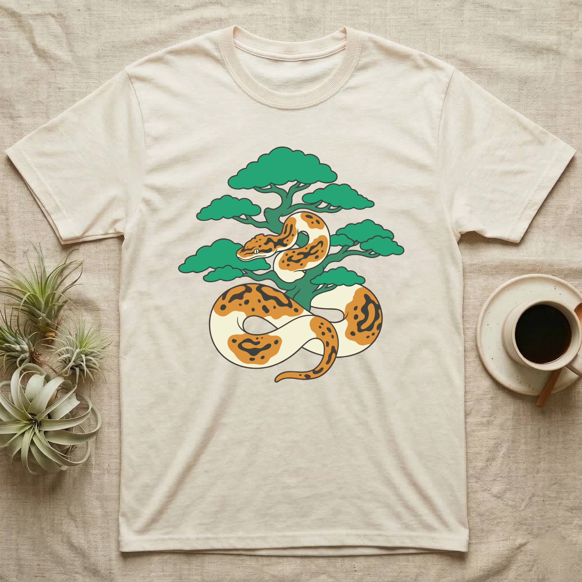 Ball python wrapped around a stylized tree on a cream t-shirt.